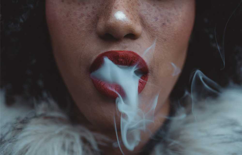 woman with red lips exhaling smoke