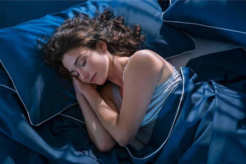 woman sleeping on her side with blue bedding