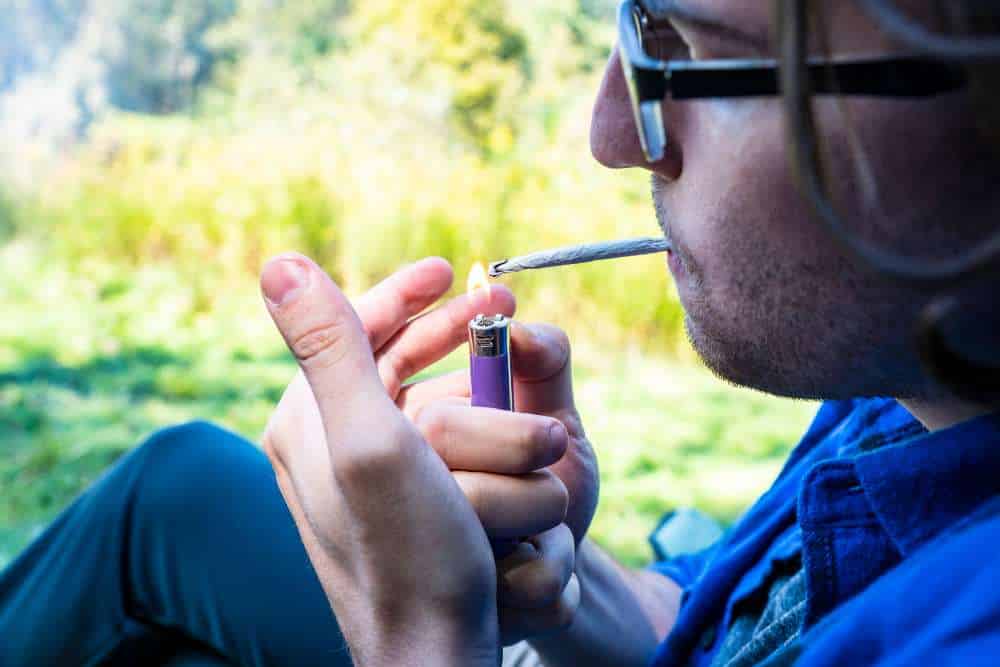 man with glasses lighting joint
