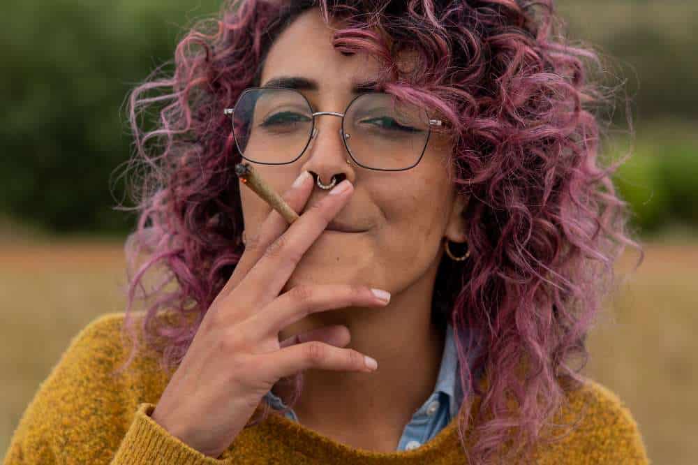 woman with pink hair smoking joint