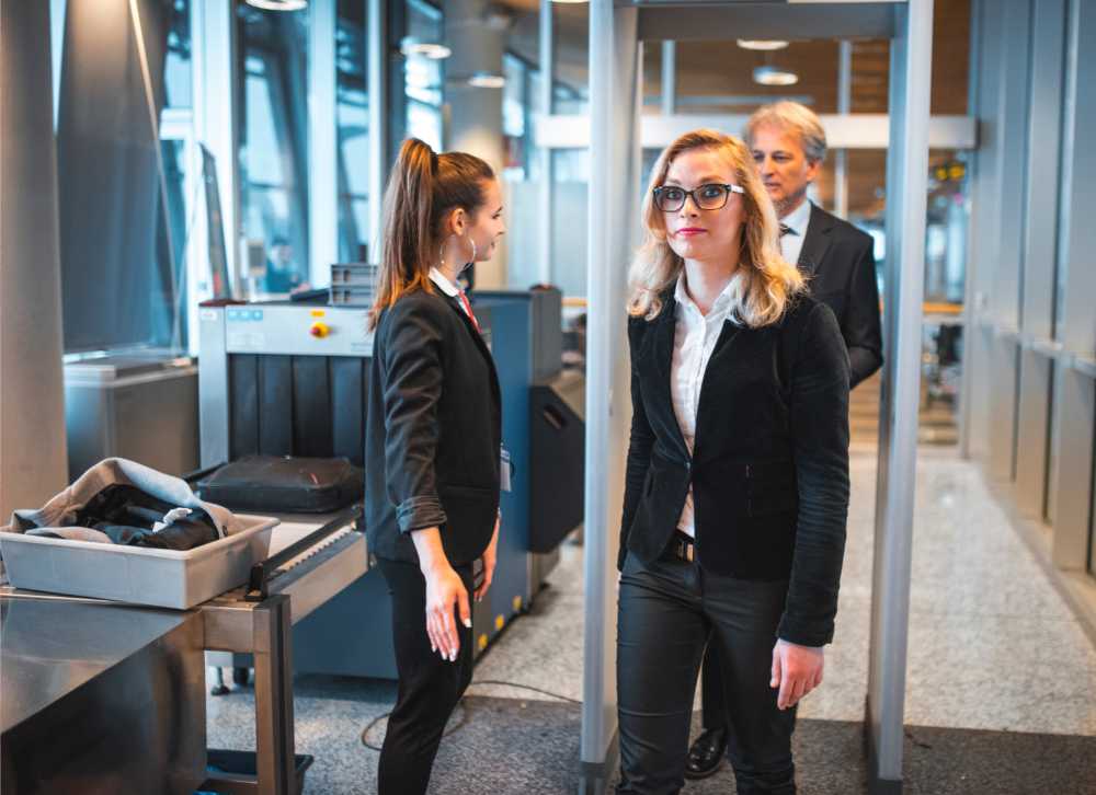 blond woman with glasses walking through metal detector