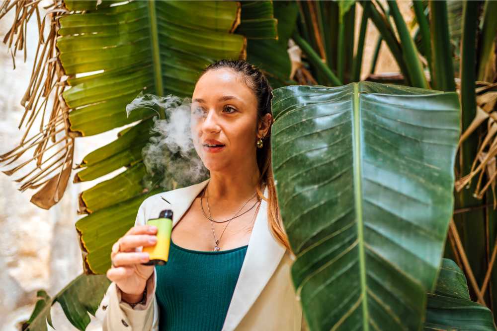 woman vaping near large green tropical plant