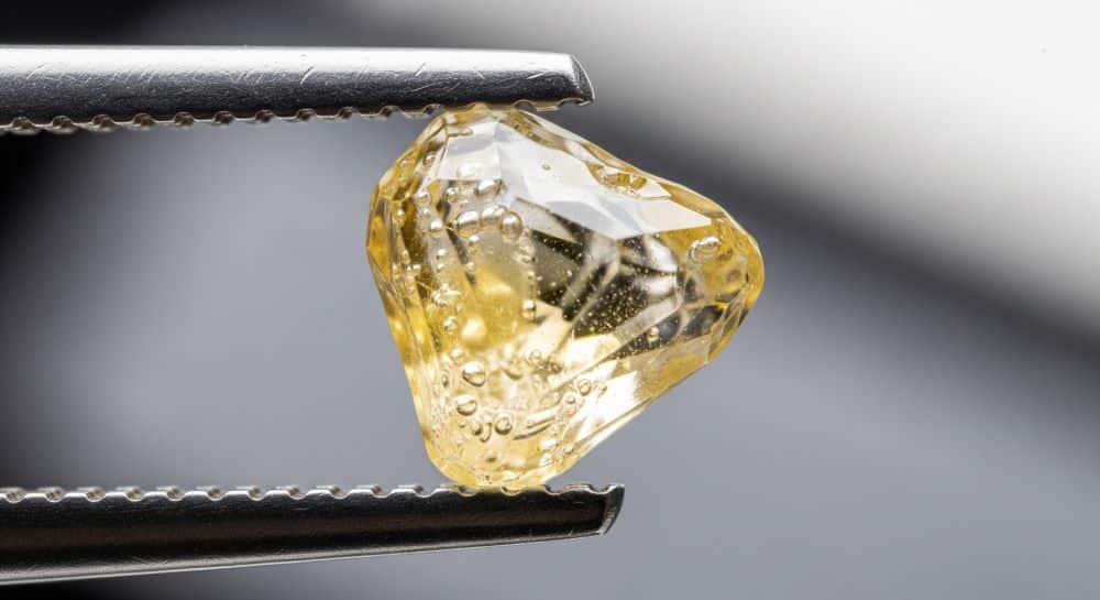 closeup of thca diamond crystal between tweezers